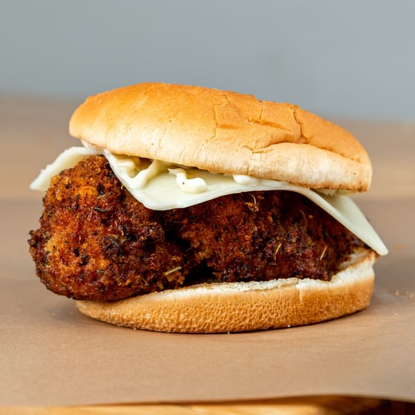 Crispy fried chicken sandwich with melted white cheese and mayonnaise on a toasted bun.