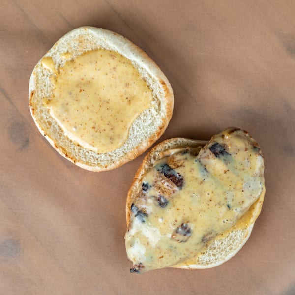 Top-down view of an open chicken sandwich with creamy sauce on a bun.