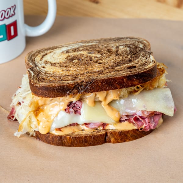 A deli sandwich with pastrami, Swiss cheese, sauerkraut, and Russian dressing on marbled rye.